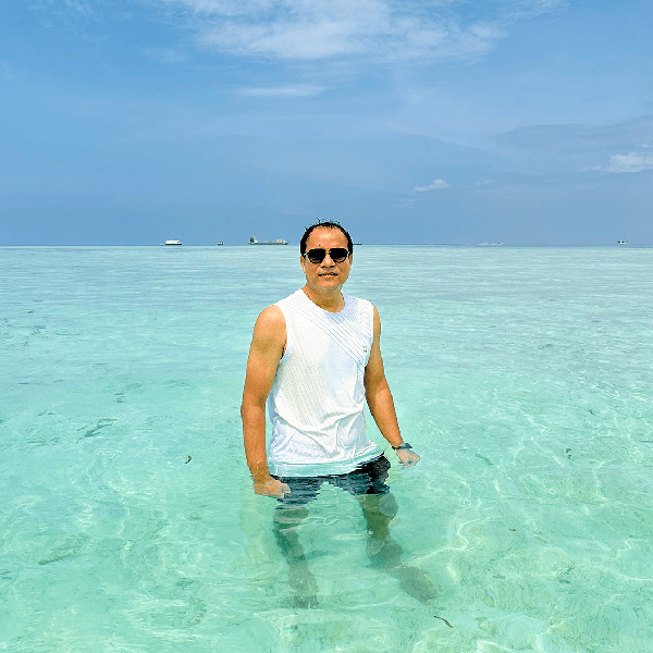 Billal standing in clear turquoise water beneath a blue sky